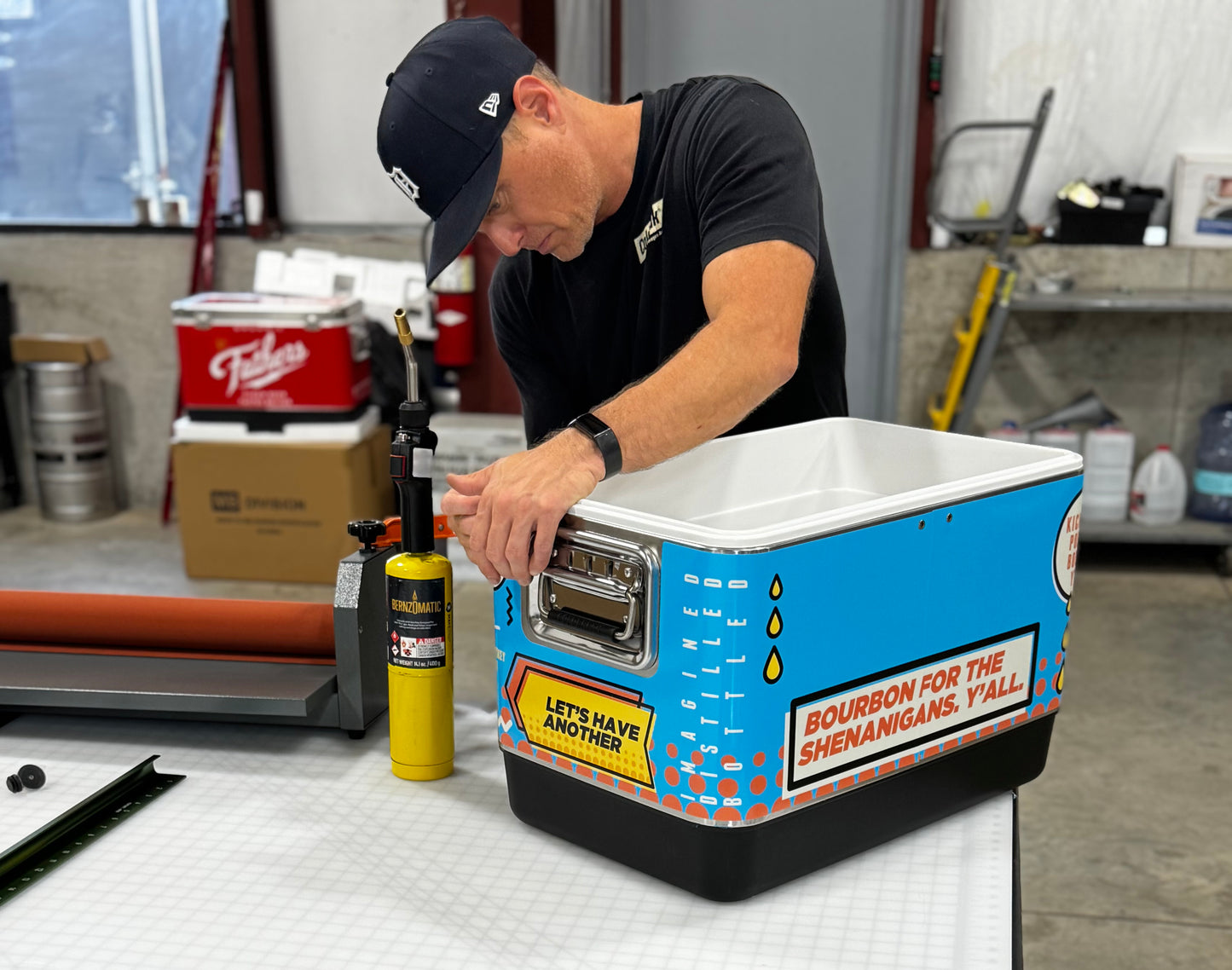 Person working on a cooler with a colorful design in a workshop setting. Jockey Box cooler wrap by Coldbreak.