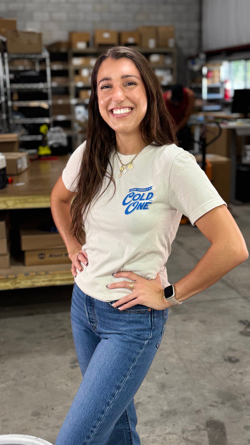 Woman wearing a t-shirt with 'COLD ONE' logo in a warehouse setting