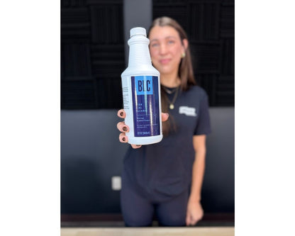 Person holding a bottle labeled 'BLC' against a dark background, beer line cleaner