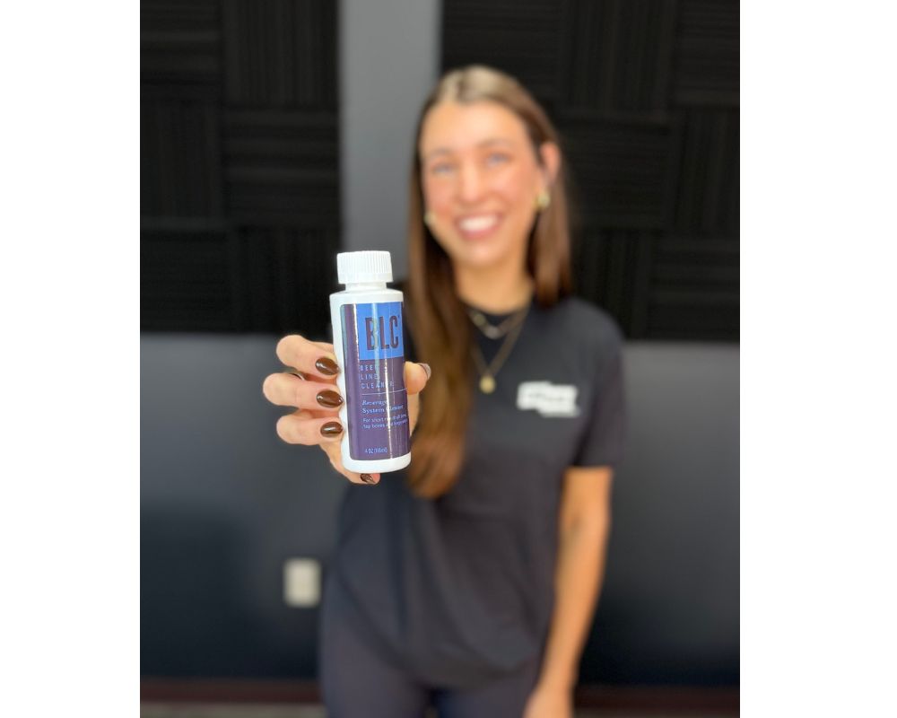Person holding a bottle labeled 'BLC' in an indoor setting beer line cleaner