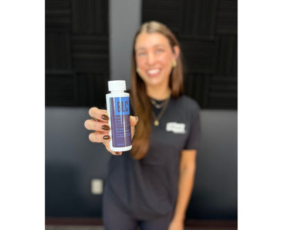 Person holding a bottle labeled 'BLC' in an indoor setting beer line cleaner