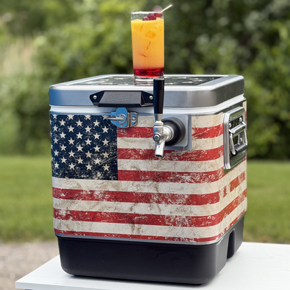 ColdOne Go draft cooler with American flag design on table with cocktail on top