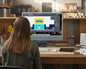 Person sitting at a desk using a computer with a design software open on the screen.